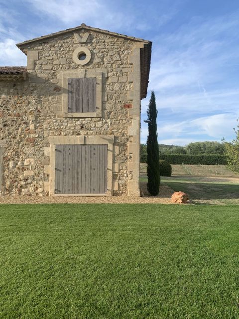 Mas provençal en pierre avec volets en bois, entouré d'un jardin verdoyant et d'un cyprès, typique de l'architecture du Luberon