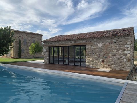 Pool house en pierre de style provençal avec baies vitrées et terrasse en bois au bord de la piscine, Luberon
