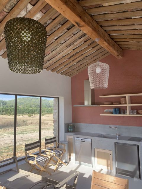Intérieur moderne du pool house en pierre à Roussillon, Luberon, avec plafond en bois et vue sur la campagne