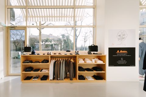 Vue intérieure du magasin avec mobilier bois clair et présentoirs de vêtements